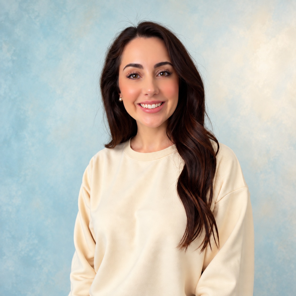 Dr. Christina Amiot smiling in a cream sweater against a soft blue background